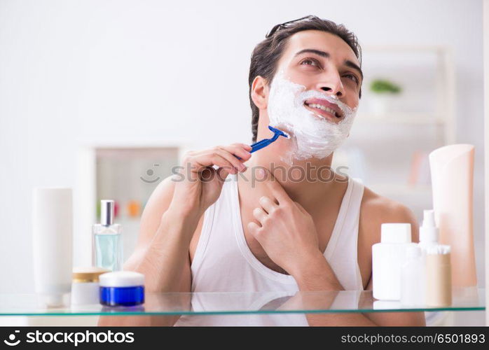 Young handsome man shaving early in the morning at home