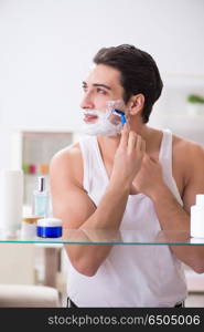 Young handsome man shaving early in the morning at home