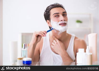 Young handsome man shaving early in the morning at home