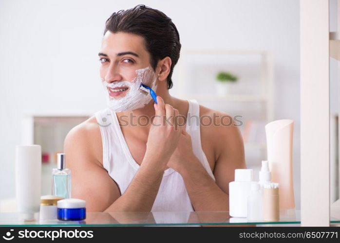 Young handsome man shaving early in the morning at home