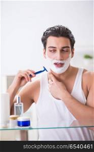 Young handsome man shaving early in the morning at home