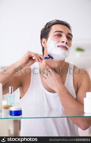 Young handsome man shaving early in the morning at home