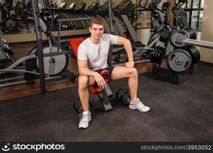 young handsome man sits after workout in the gym