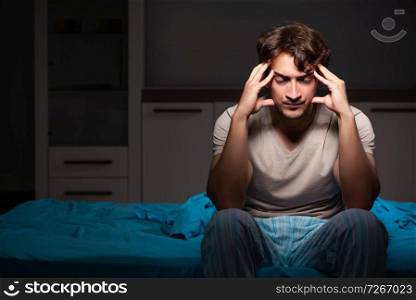 Young handsome man suffering from insomnia in bed