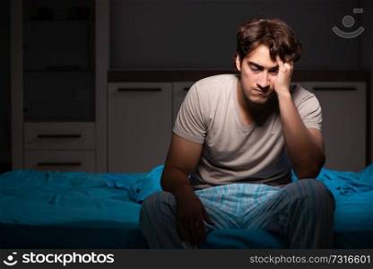 Young handsome man suffering from insomnia in bed