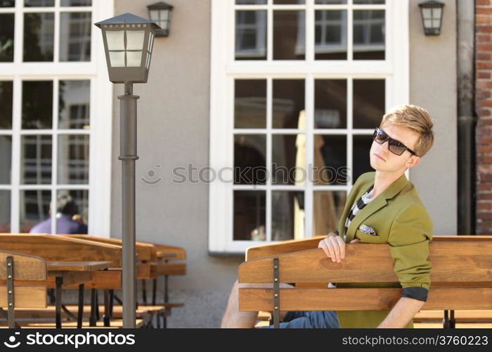 Young handsome man traveler casual style sitting on bench waits, old town Gdansk Poland Europe