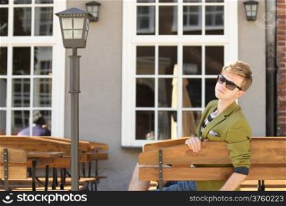 Young handsome man traveler casual style sitting on bench waits, old town Gdansk Poland Europe