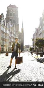 Young handsome man traveler casual style with suitcase baggage on street of old town Gdansk Poland Europe