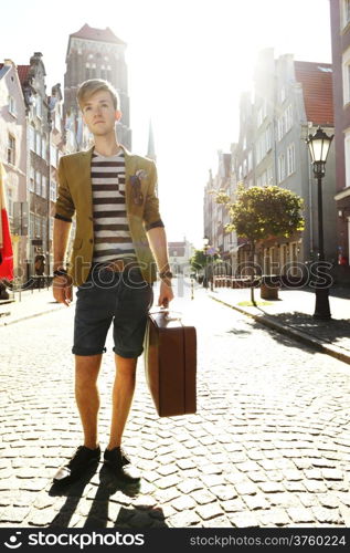 Young handsome man traveler casual style with suitcase baggage on street of old town Gdansk Poland Europe