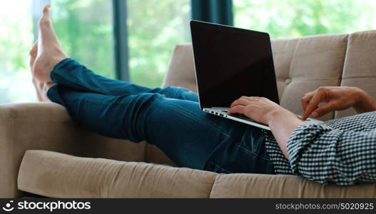 Young, handsome man using laptop sitting on sofa