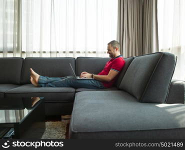 Young, handsome man using laptop sitting on sofa