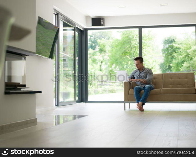 Young, handsome man using laptop sitting on sofa