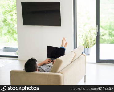 Young, handsome man using laptop sitting on sofa