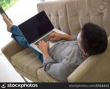 Young, handsome man using laptop sitting on sofa