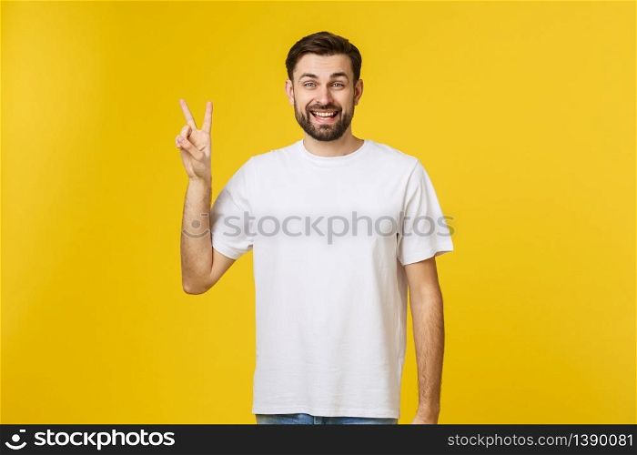 Young handsome man wearing striped t-shirt over isolated yellow background smiling looking to the camera showing fingers doing victory sign. Number two.. Young handsome man wearing striped t-shirt over isolated yellow background smiling looking to the camera showing fingers doing victory sign. Number two
