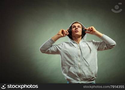 young handsome man with headphones listening to music looking up grunge background
