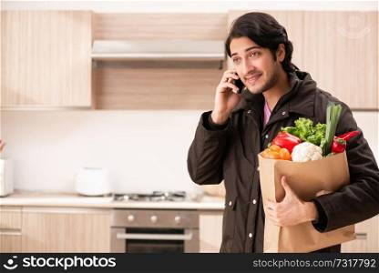 Young handsome man with vegetables in the kitchen 