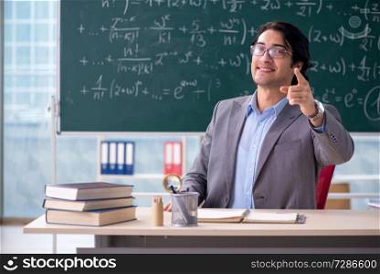 Young handsome math teacher in classroom 
