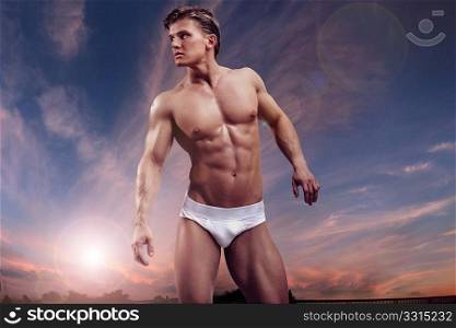 Young handsome muscular guy over twilight sky