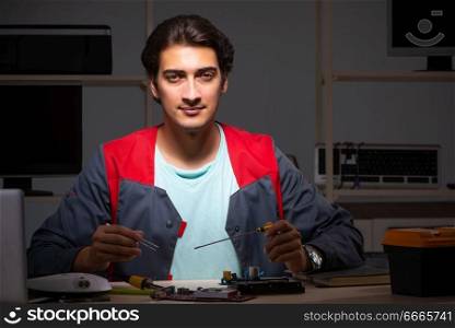 Young handsome repairman repairing computer 