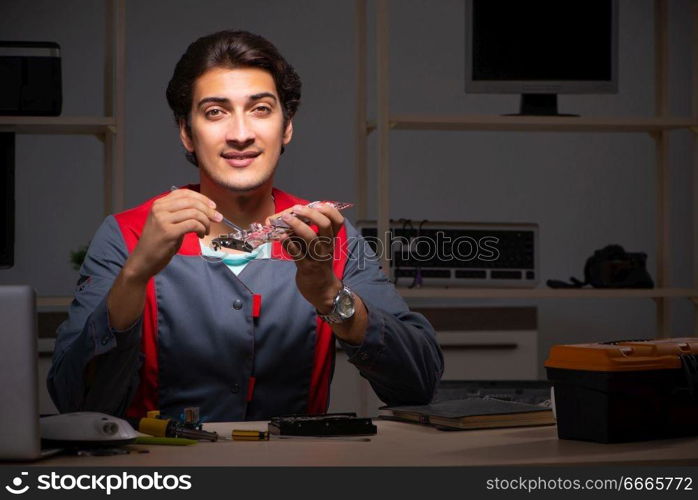 Young handsome repairman repairing computer 