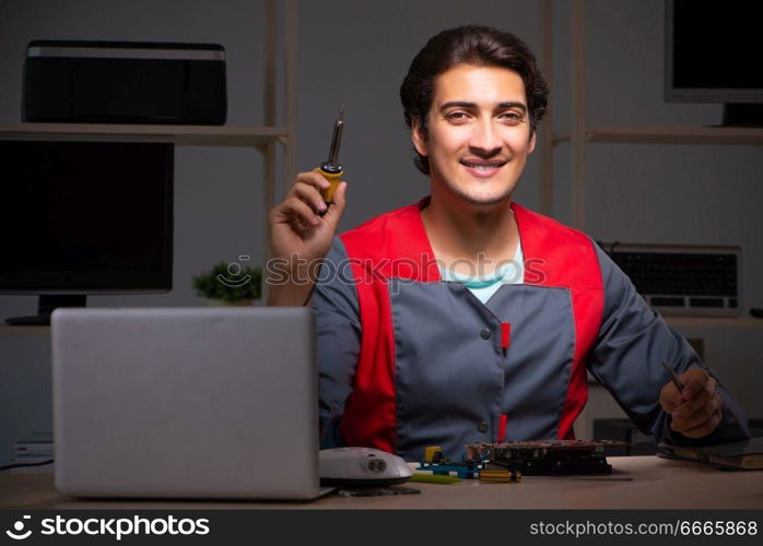 Young handsome repairman repairing computer 