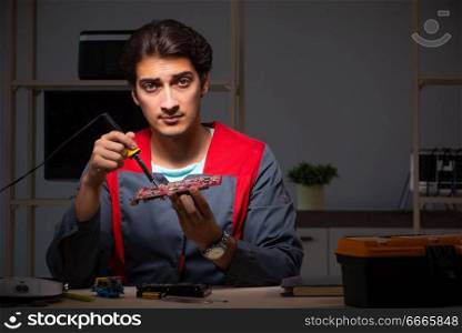 Young handsome repairman repairing computer . The young handsome repairman repairing computer 