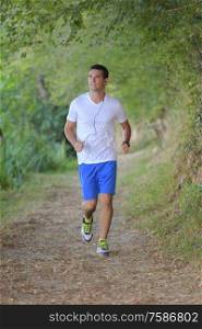 young handsome runner with earphones outside in nature