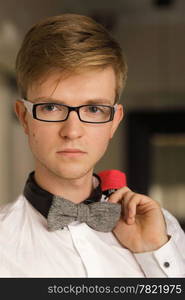 Young handsome stylish man fashion model in glasses wearing white shirt and bow tie posing indoor