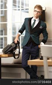 Young handsome stylish man fashion model posing in trendy cafe /restaurant with bag