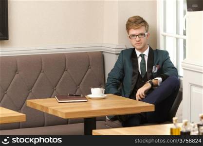 Young handsome stylish man fashion model relaxing thinking and waiting in cafe /restaurant with coffee