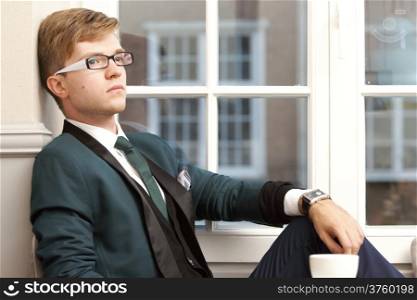Young handsome stylish man fashion model relaxing thinking and waiting in cafe /restaurant with coffee