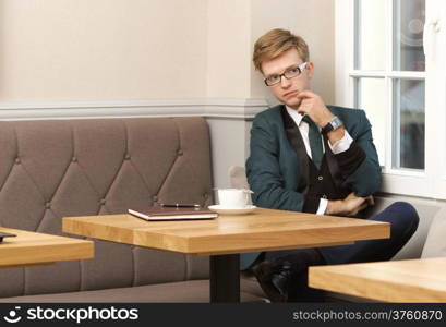 Young handsome stylish man fashion model relaxing thinking and waiting in cafe /restaurant with coffee