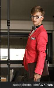 Young handsome stylish man fashion model wearning bright red jacket and bow tie with notebook posing indoor