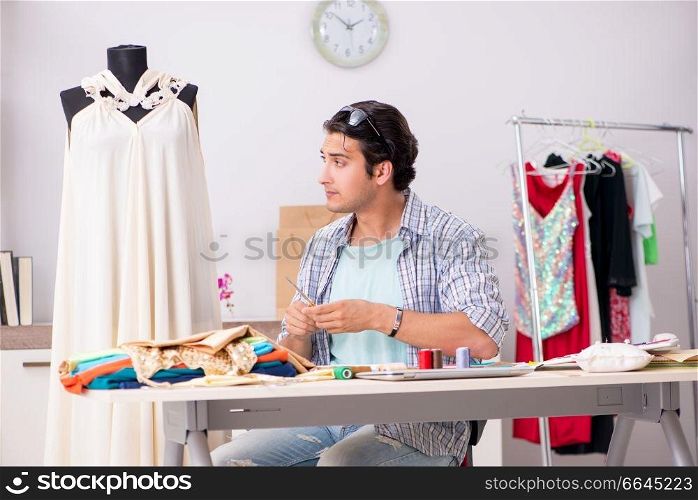 Young handsome tailor working in his workshop. The young handsome tailor working in his workshop
