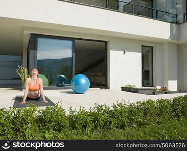 young handsome woman doing morning yoga exercises in front of her luxury home villa