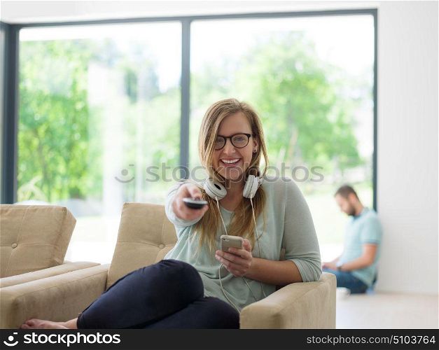 young handsome woman enjoying free time watching television in her luxury home villa