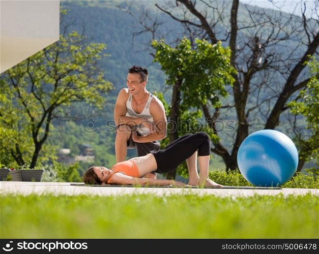 young handsome woman with personal trainer doing morning yoga exercises in front of her luxury home villa