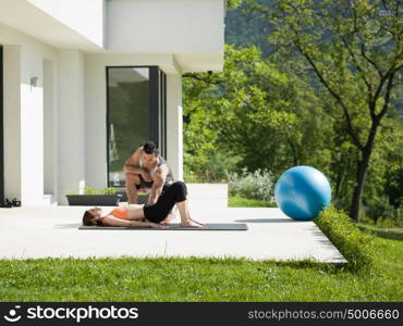 young handsome woman with personal trainer doing morning yoga exercises in front of her luxury home villa