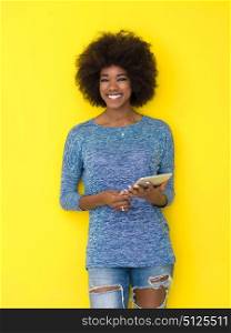 Young Happy African American Woman Using Digital Tablet Isolated on a yellow background