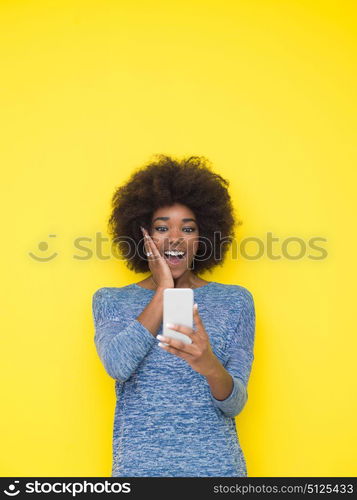 Young Happy African American Woman Using mobile phone Isolated on a yellow background