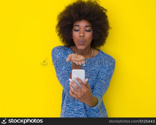 Young Happy African American Woman Using mobile phone Isolated on a yellow background