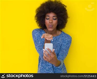 Young Happy African American Woman Using mobile phone Isolated on a yellow background