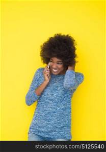 Young Happy African American Woman Using mobile phone Isolated on a yellow background