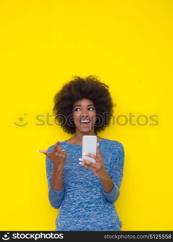 Young Happy African American Woman Using mobile phone Isolated on a yellow background