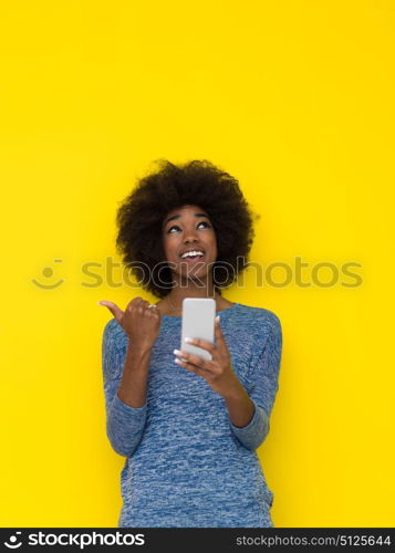 Young Happy African American Woman Using mobile phone Isolated on a yellow background