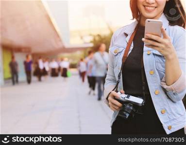 Young happy asian woman enjoying travel while using smartphone navigation and communicating at the street in the city