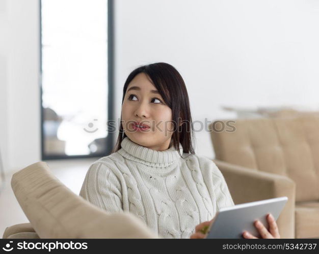 young happy asian woman sitting on sofa using Digital Tablet