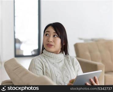 young happy asian woman sitting on sofa using Digital Tablet
