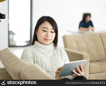 young happy asian woman sitting on sofa using Digital Tablet